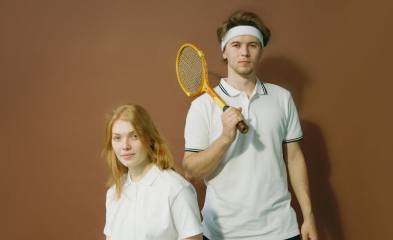 Portrait of a young male and female tennis players in white attire posing indoors with a vintage racket.