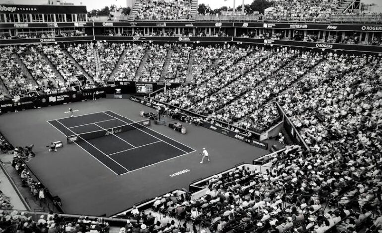 A black and white photo capturing a thrilling tennis match in a crowded outdoor stadium.