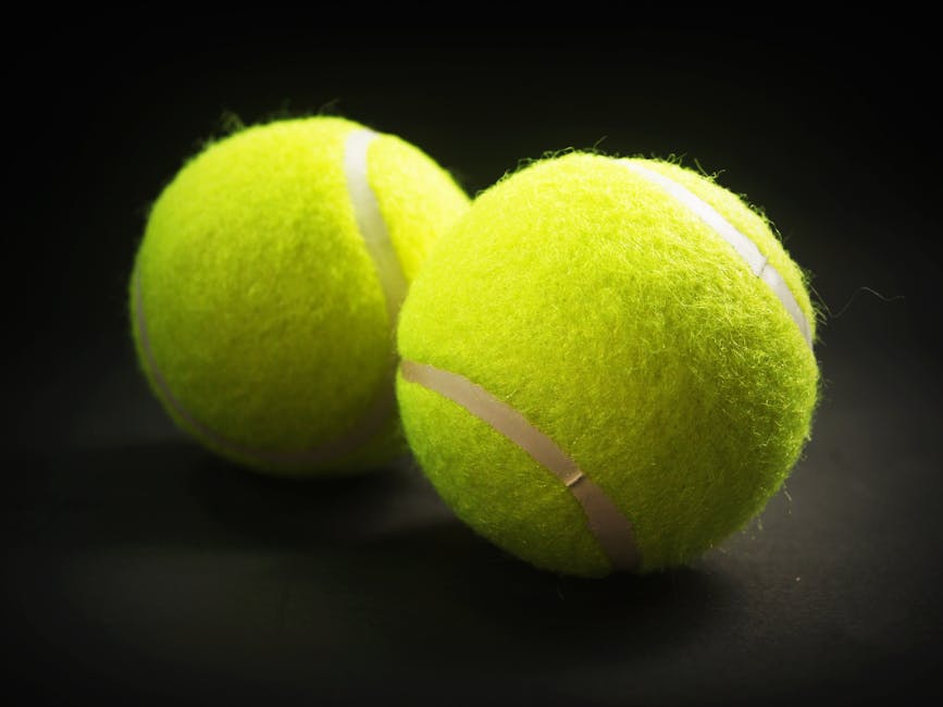 Close-up of two tennis balls with a vibrant yellow color on a dark background.