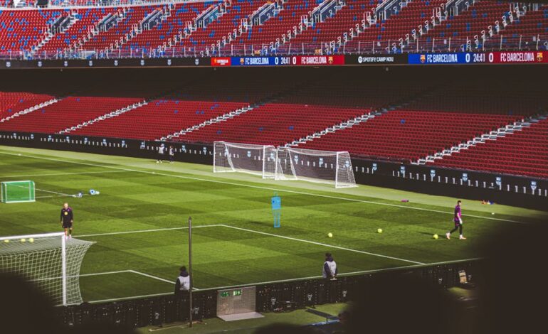 Soccer practice at a famous stadium with vibrant red seating and green field.