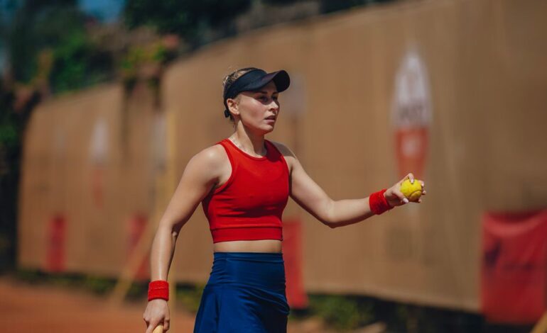 Focused female tennis player in action on an outdoor clay court during daytime.