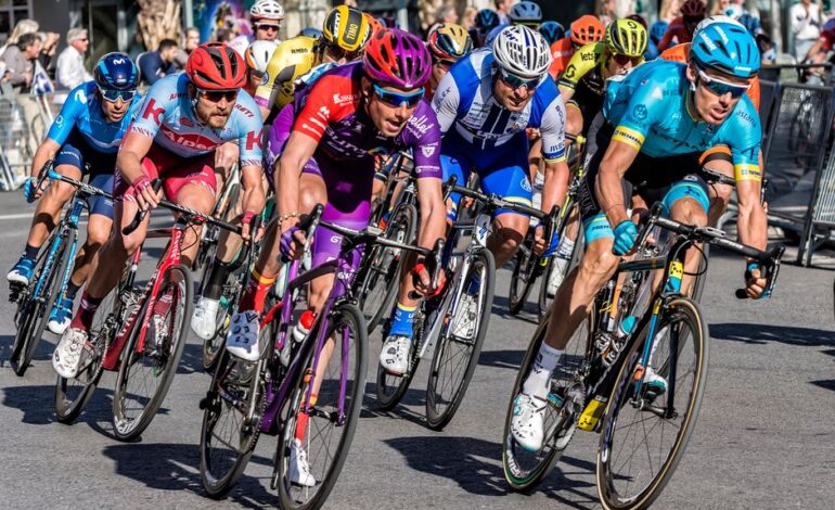 Competitive cyclists in vibrant gear race through Alicante streets, showcasing speed and athleticism.
