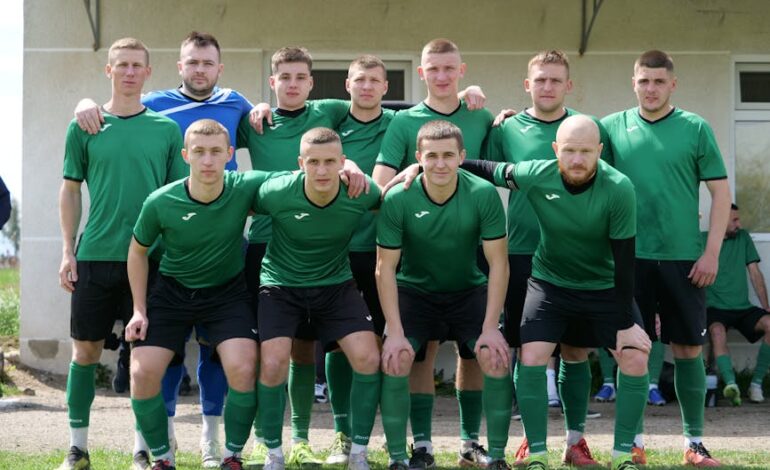 A group of amateur soccer players posing together in sportswear outdoors.