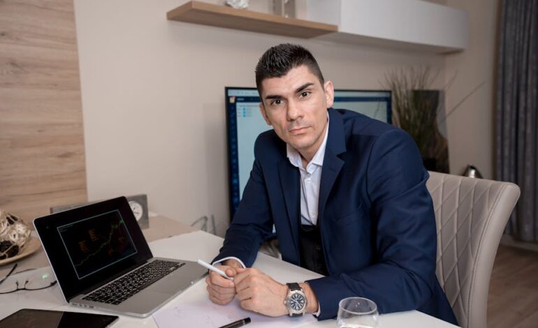 Businessman in blue suit working on laptop in sleek office setting, conveying professionalism and focus.