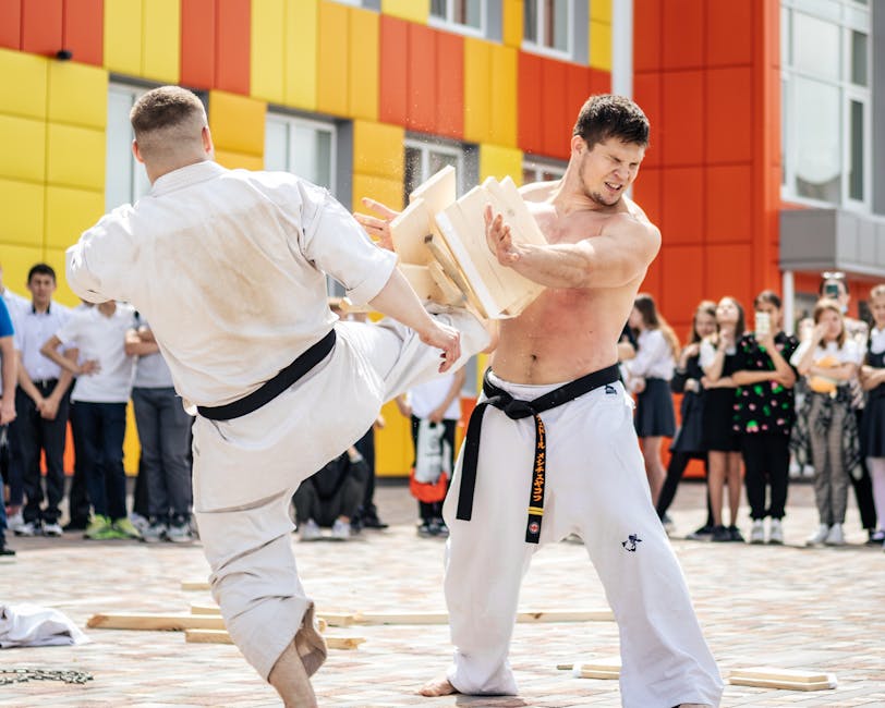 Martial artists perform a powerful board breaking demonstration in front of an engaged audience.