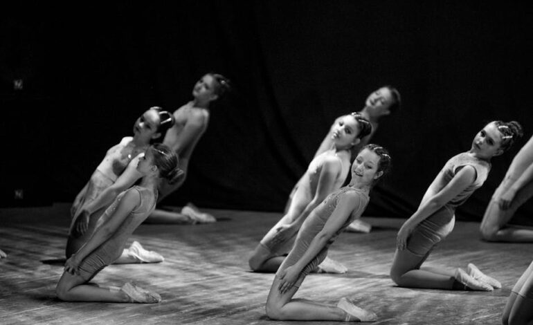 Captivating black and white photo of young ballet dancers performing on a dimly lit stage.