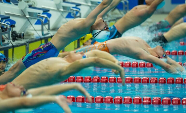 Athletes dive into the pool at a vibrant swimming competition.