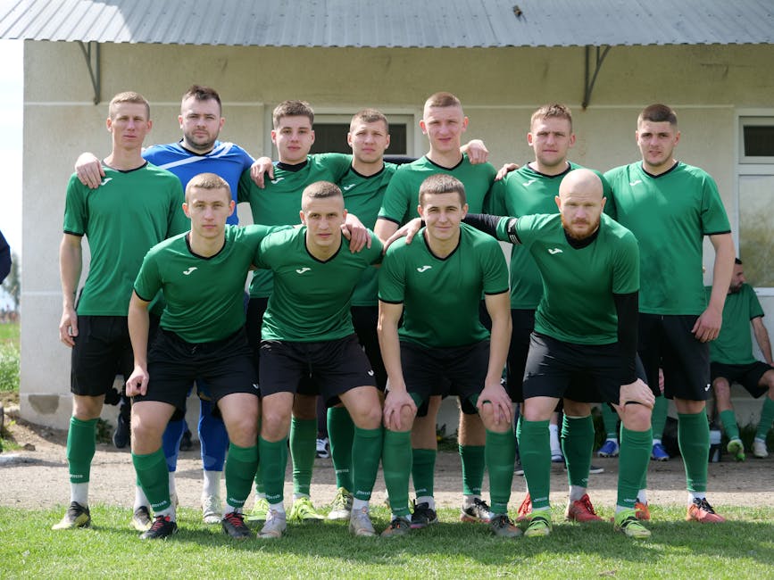 A group of amateur soccer players posing together in sportswear outdoors.