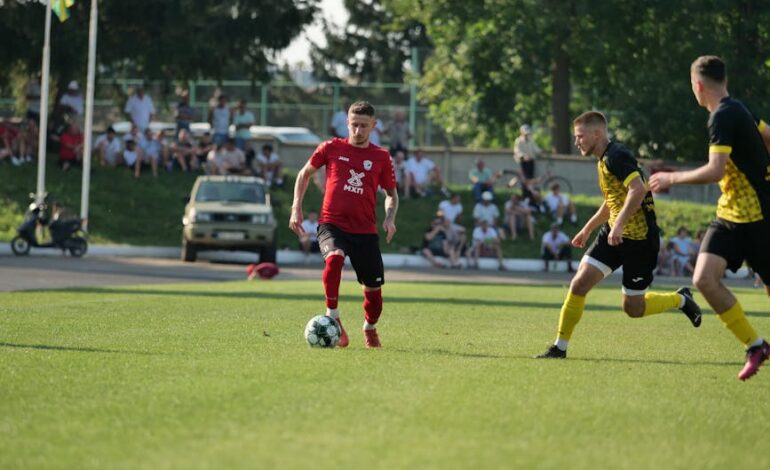 A competitive outdoor soccer match featuring players in dynamic action on a sunny day.