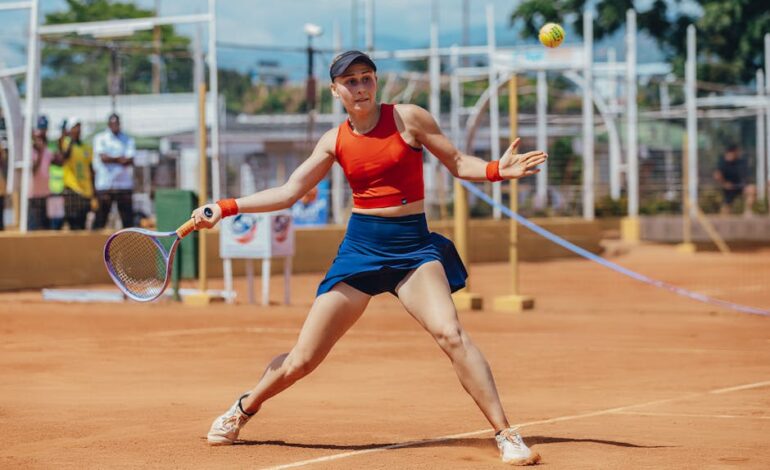 Dynamic shot of a female tennis player hitting a forehand on a clay court during a sunny day.