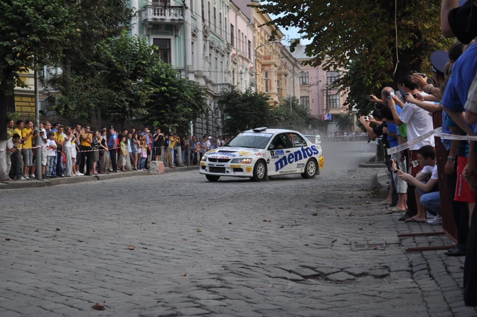 Thrilling car rally event with spectators on a historic cobblestone street.