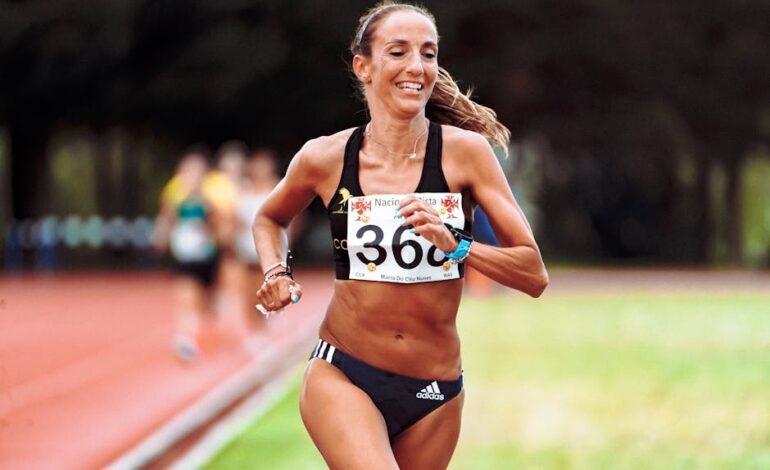 Happy fit ethnic female runner in active wear running on race track during athletic contest in summer