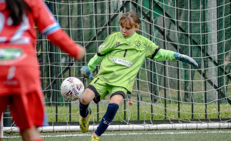 Young soccer goalie in action during a youth match, capturing a dynamic play.