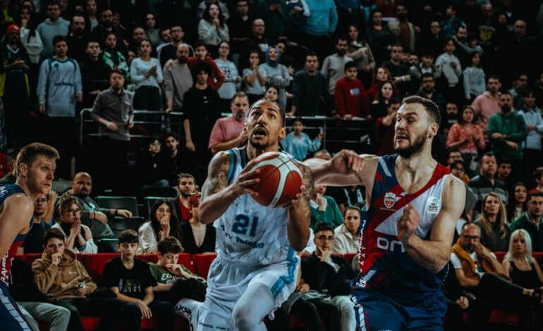 Dynamic action shot from a live basketball game capturing the competition and audience involvement.