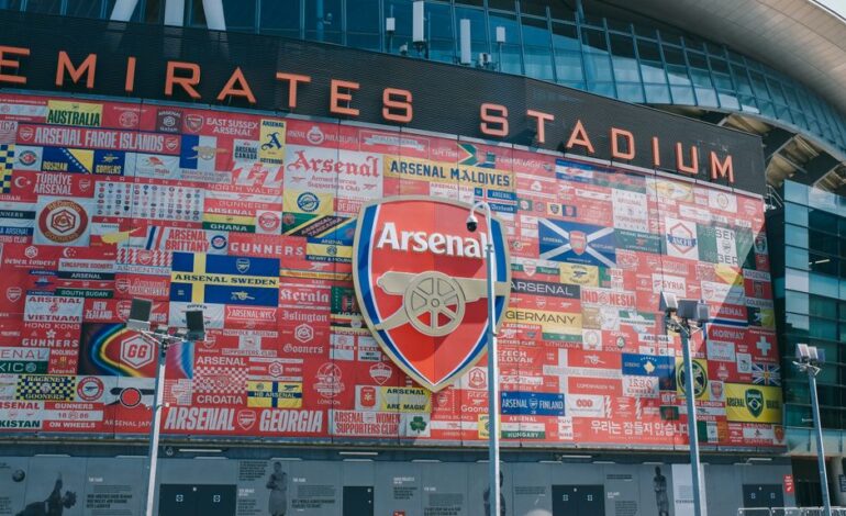 Vibrant wall art at Emirates Stadium featuring Arsenal flags and crest in London, UK.