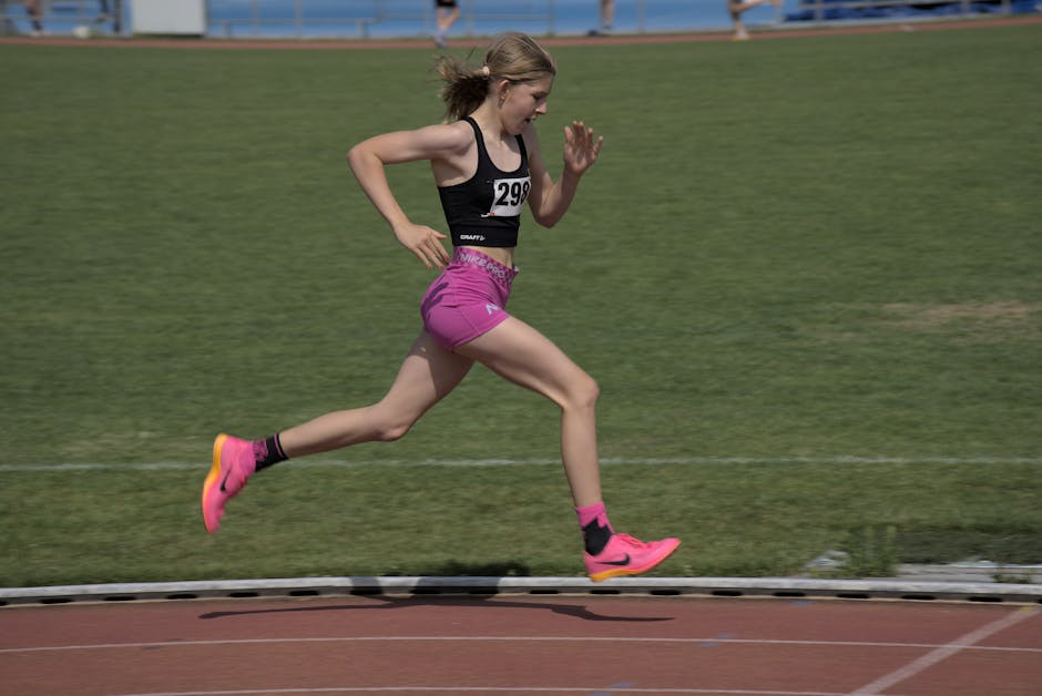 A teenage girl sprinting on a track during a sports race at a stadium.