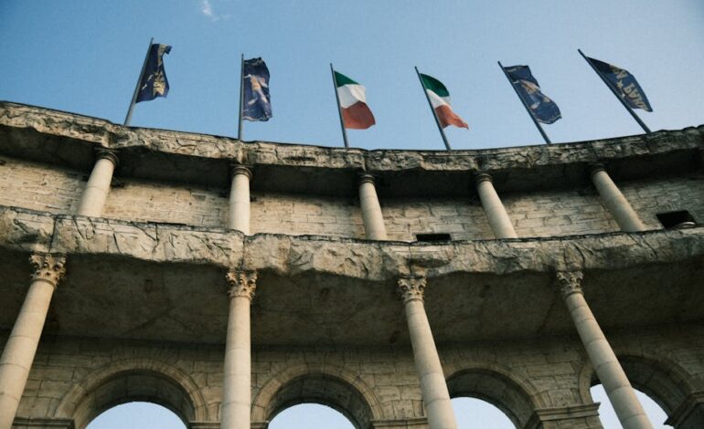 View of Colosseum arches with various flags under a clear sky.