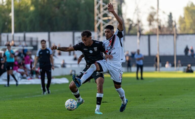Dynamic shot capturing two footballers vying for the ball during an outdoor soccer match.