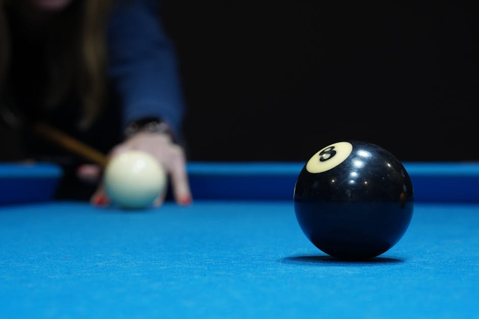 Focused view of the eight ball and cue ball on a blue pool table, ready for a shot.
