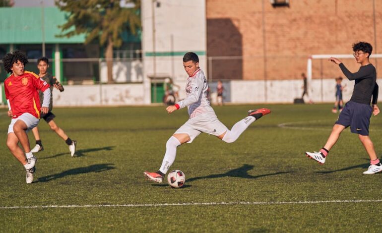 Energetic soccer match with teenagers competing on a sunny outdoor field.