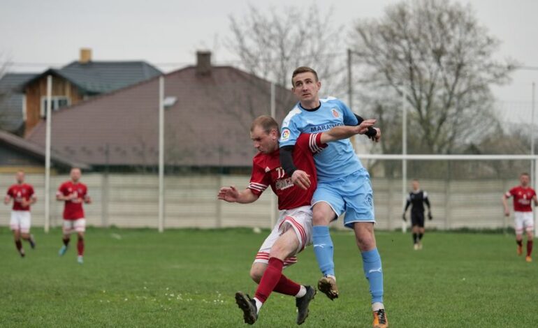 Players fiercely competing in a local football match on an outdoor grassy field.