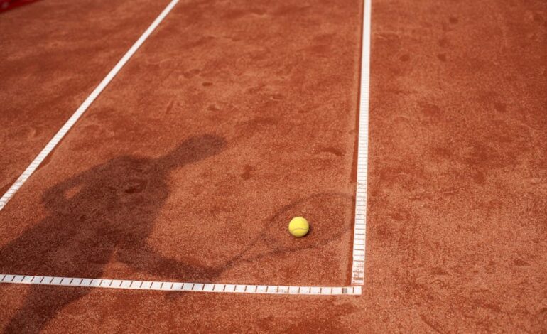 Shadow of a tennis player on a clay court with a yellow tennis ball. Perfect for sports and tennis themes.
