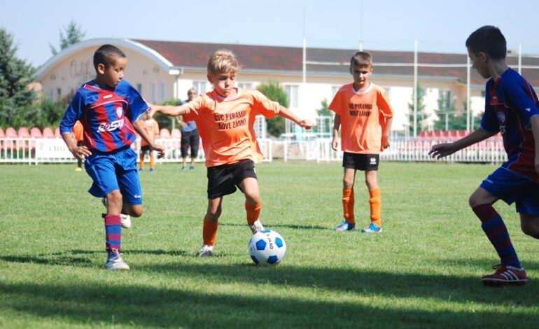 Young boys playing a competitive soccer match outdoors on a sunny day.