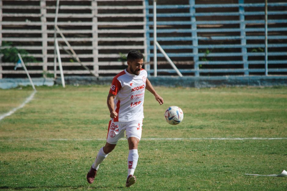 Soccer player in white kit playing on a field in Mendoza, Argentina.