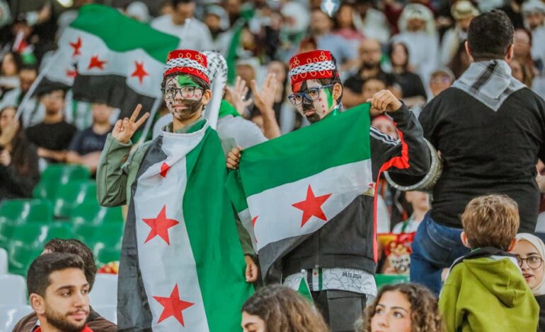 Supporters with Syrian flags at a sports event in Doha, capturing the vibrant and festive spirit.