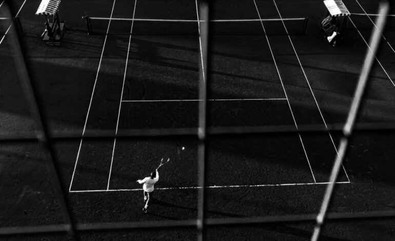 Black and white photo of a tennis match in Buenos Aires, capturing dynamic motion and shadow play.