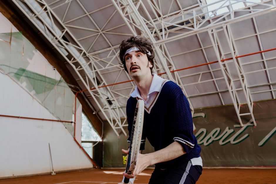 Focused tennis player poised on an indoor court, ready to serve a match-winning shot.
