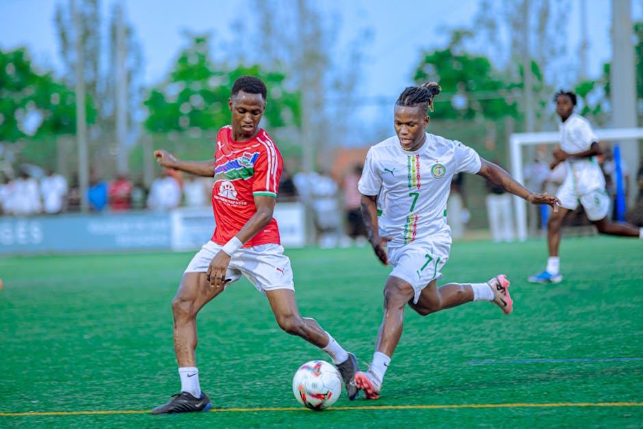 Two soccer players competing on a vibrant green field during a daytime match.