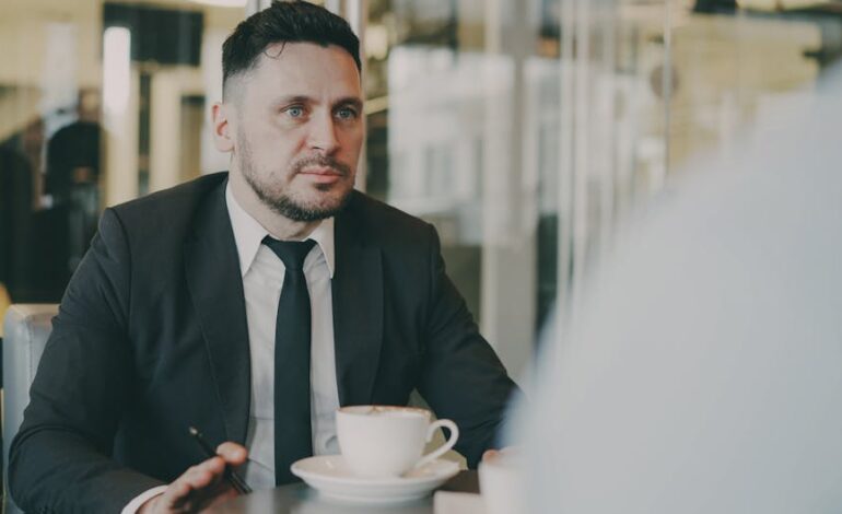 A professional in a suit engaged in a meeting over coffee in a modern café setting.