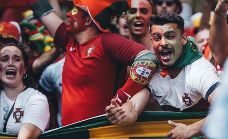 Passionate Portuguese soccer fans celebrating outdoors with flags and face paint.