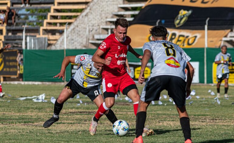 Three male soccer players competing intensely on a grassy field.