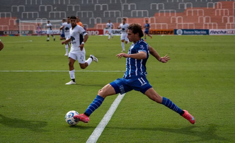 Dynamic soccer match featuring players in blue and white uniforms during a sunny day.