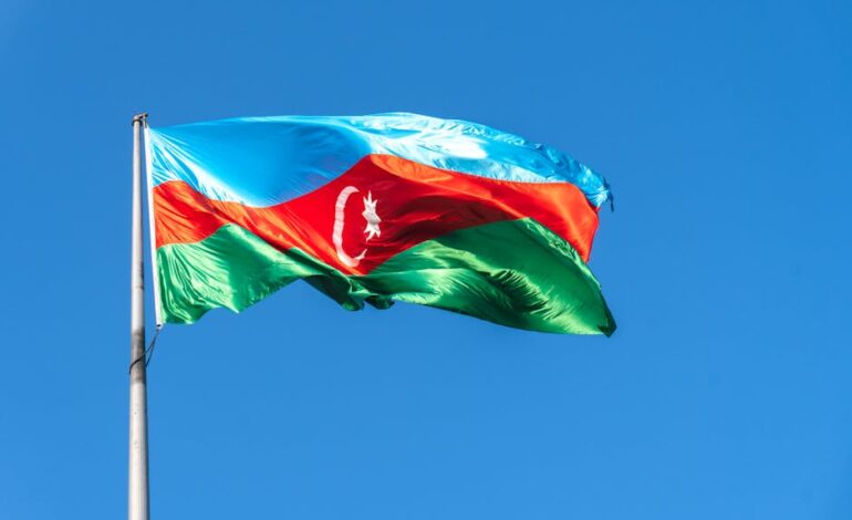 Vibrant Azerbaijan flag waving in the clear blue sky, showcasing national pride.
