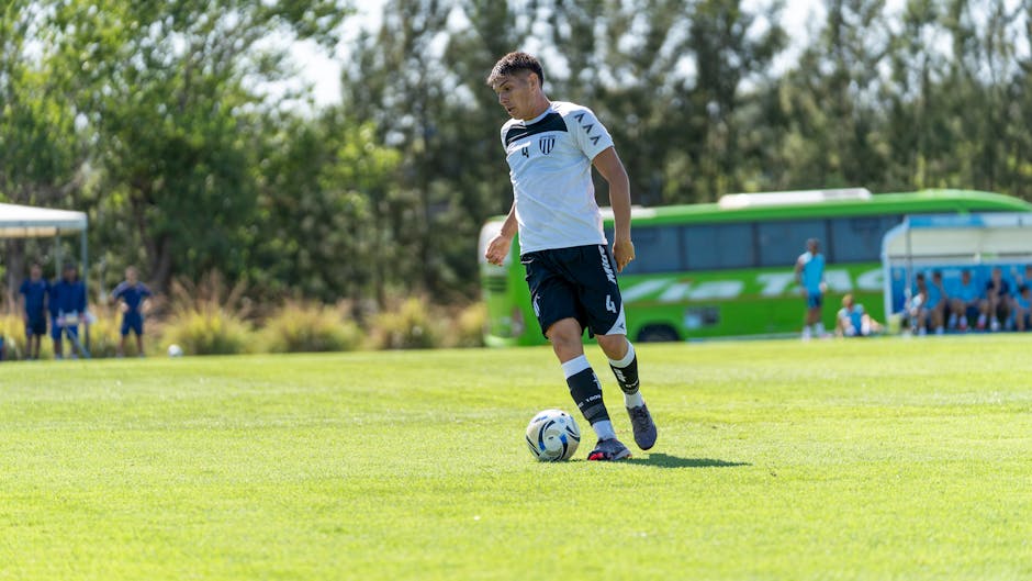Young soccer player dribbles the ball during a sunny outdoor match.