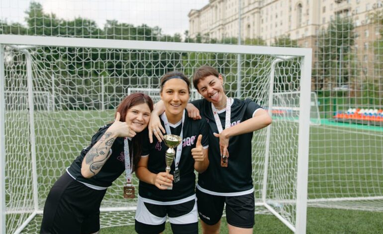 Three female soccer players celebrate their win with a trophy on an outdoor field, displaying joyful expressions and team spirit.