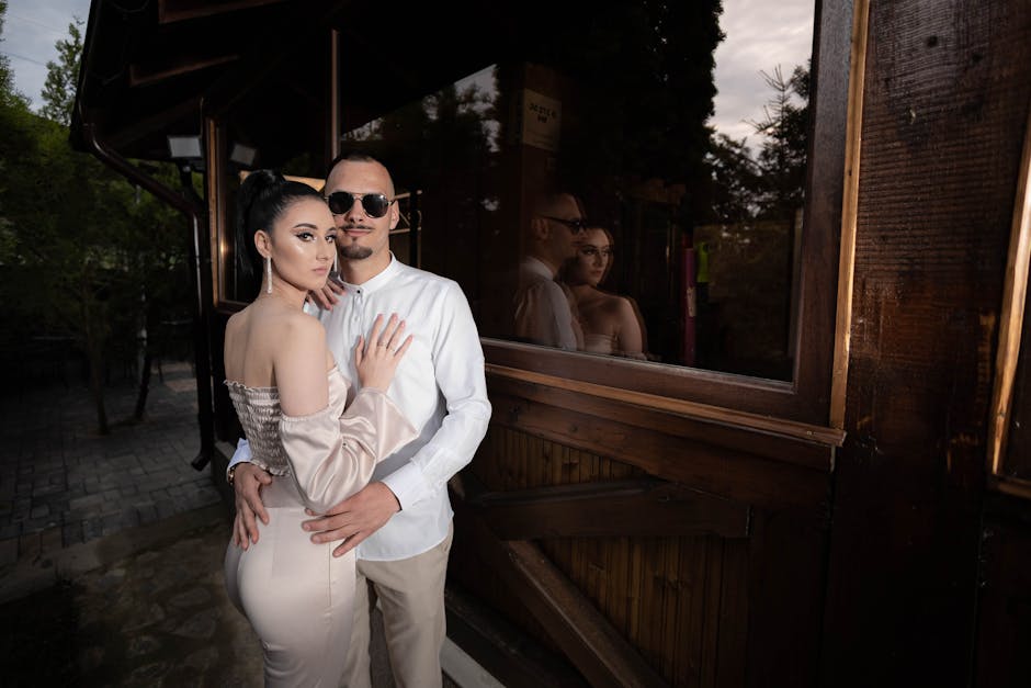 A stylish couple embraces outdoors at dusk, reflecting romance and elegance.