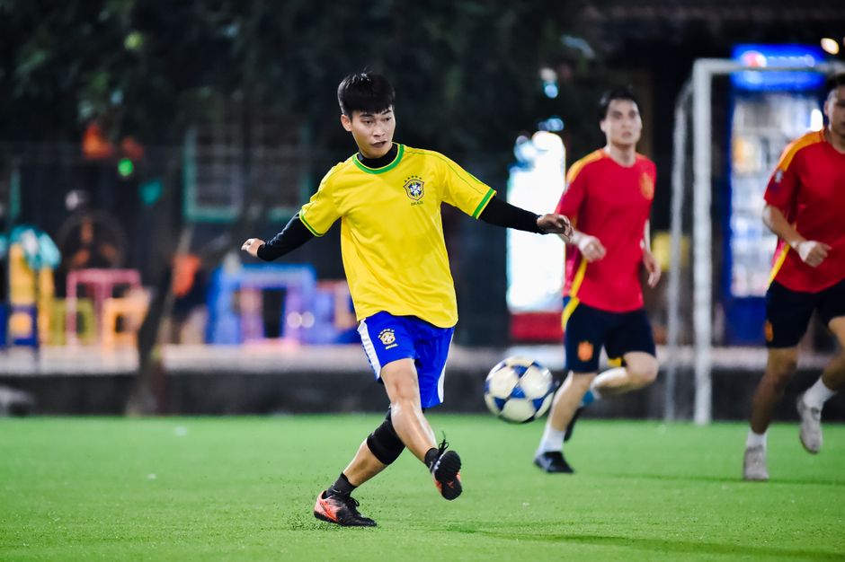 Dynamic soccer match in action at night in Hà Nội, showcasing young athletes playing on a vibrant field.