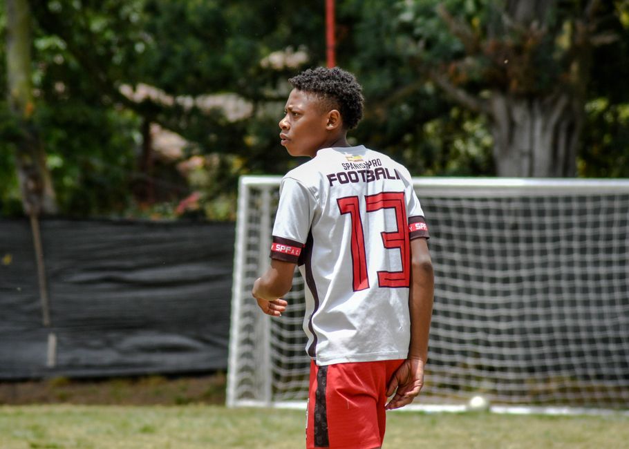 Teenager in soccer jersey with number 13 on the field, focused on the game.