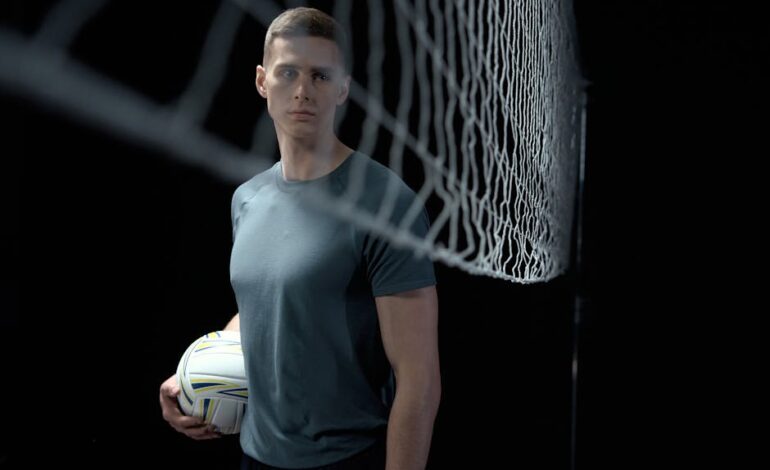 Athletic man holding a volleyball in a studio setting near a net.