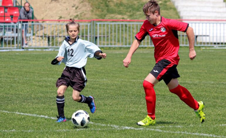 Two young soccer players engage in a competitive match on a sunny day outdoors.