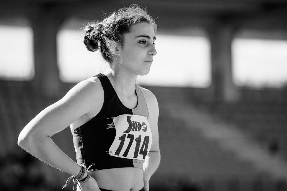 Black and white photo of a female athlete focused before a track competition, wearing bib number 1114.