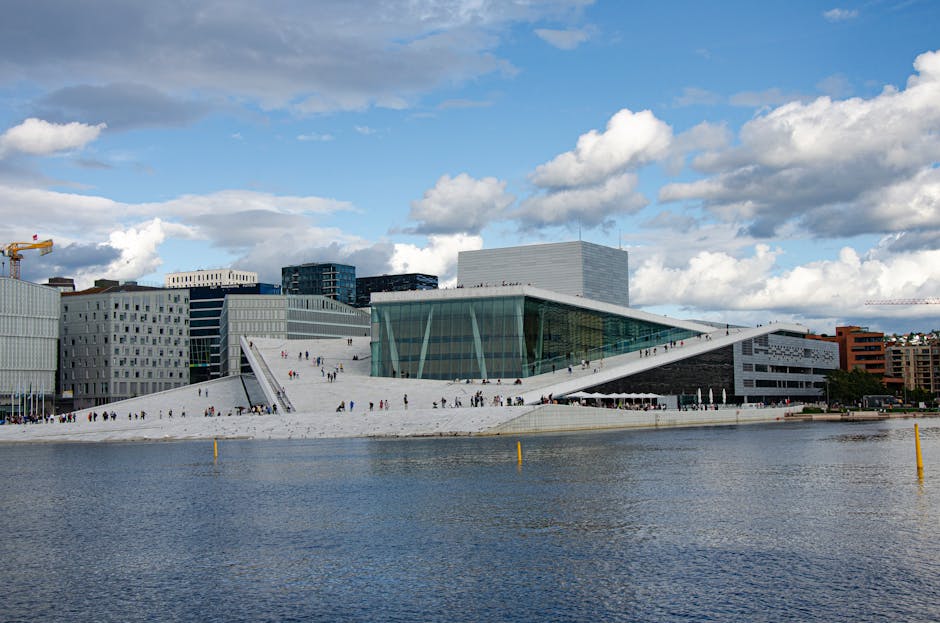 Stunning view of the Oslo Opera House by the waterfront under a blue sky, showcasing modern architecture.