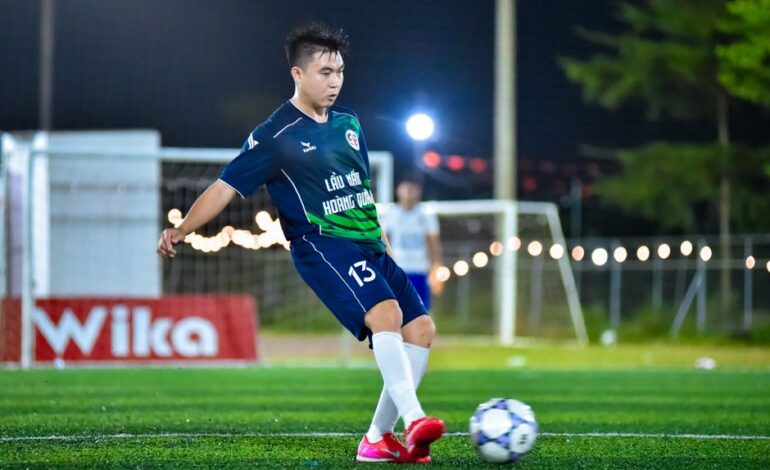 Soccer player in action on a lit field, capturing the dynamic energy of the game at night in Hà Nội.