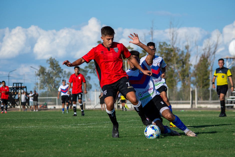 Dynamic moment of a soccer game with multiple players competing outdoors under clear skies.