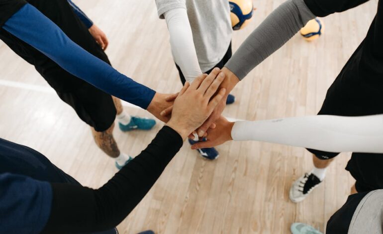 Close-up of athletes joining hands in a motivational sports huddle on an indoor court.
