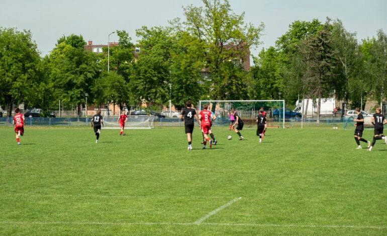 Amateur soccer players compete in a local match at a grassy field in Wrocław, Poland.